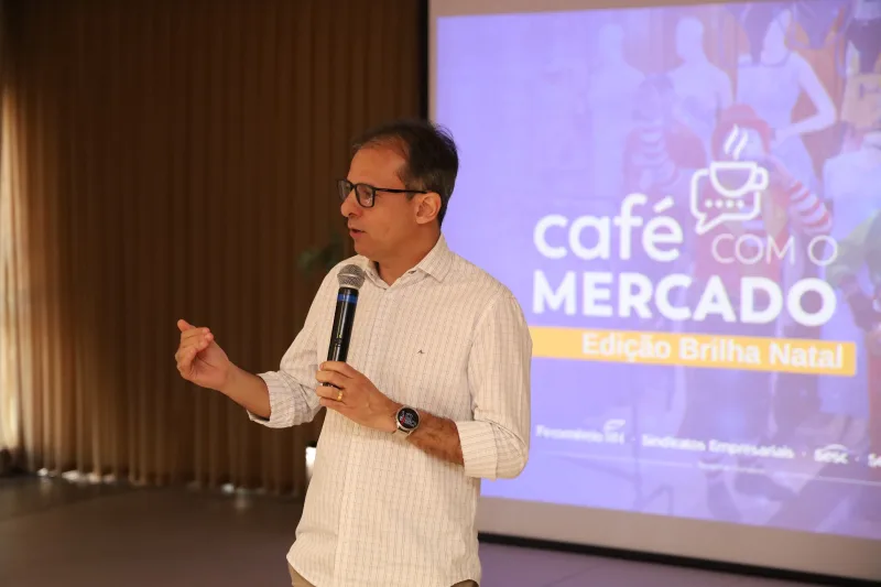 Homem de óculos discursa no evento Café com o Mercado sobre o Brilha Natal 2026