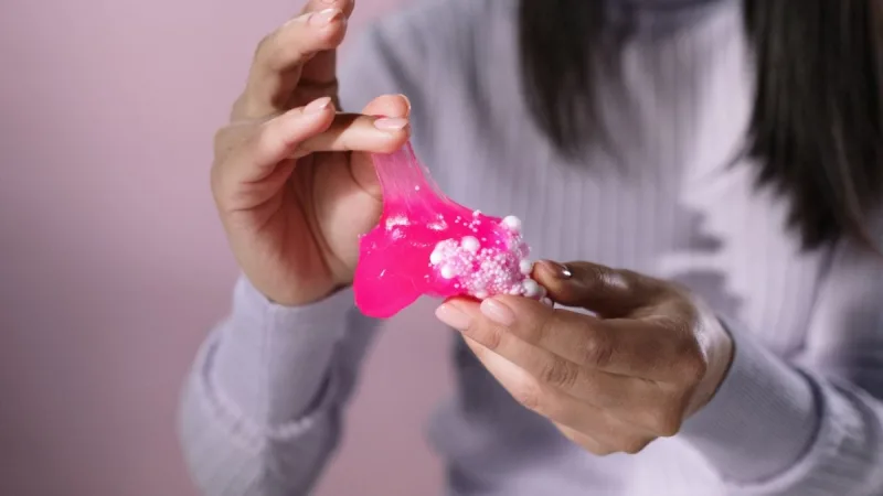 Criança mexe com slime gelatinoso em ambiente doméstico.