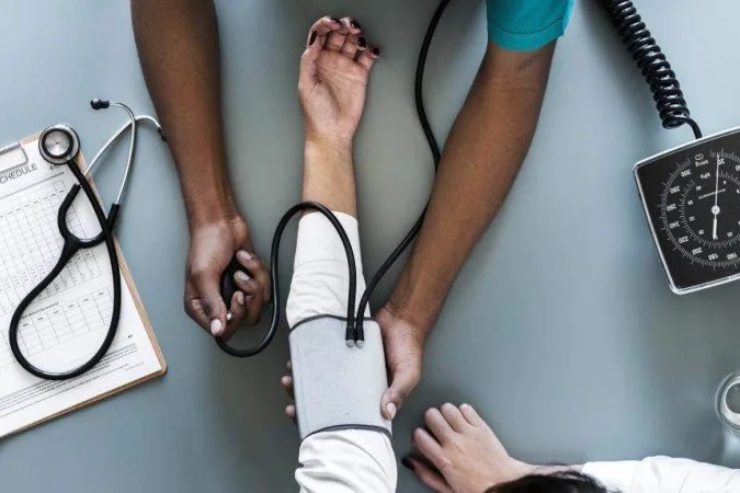 Aparelho de medir pressão arterial sobre uma mesa com um estetoscópio ao lado.