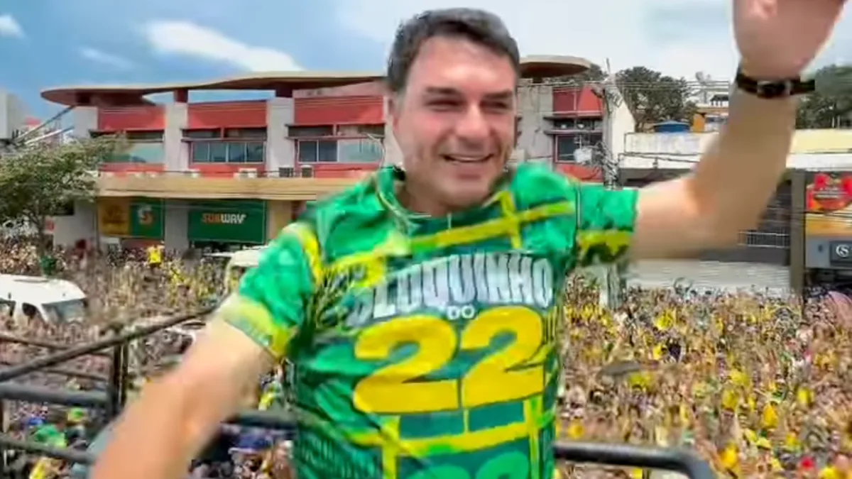 Flávio Bolsonaro dança em trio elétrico durante manifestação política em Vitória cercado por apoiadores.