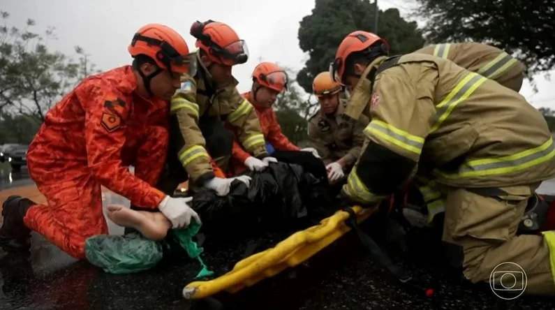 Equipe do Corpo de Bombeiros realizando o atendimento a uma vítima de acidente de moto em via pública.