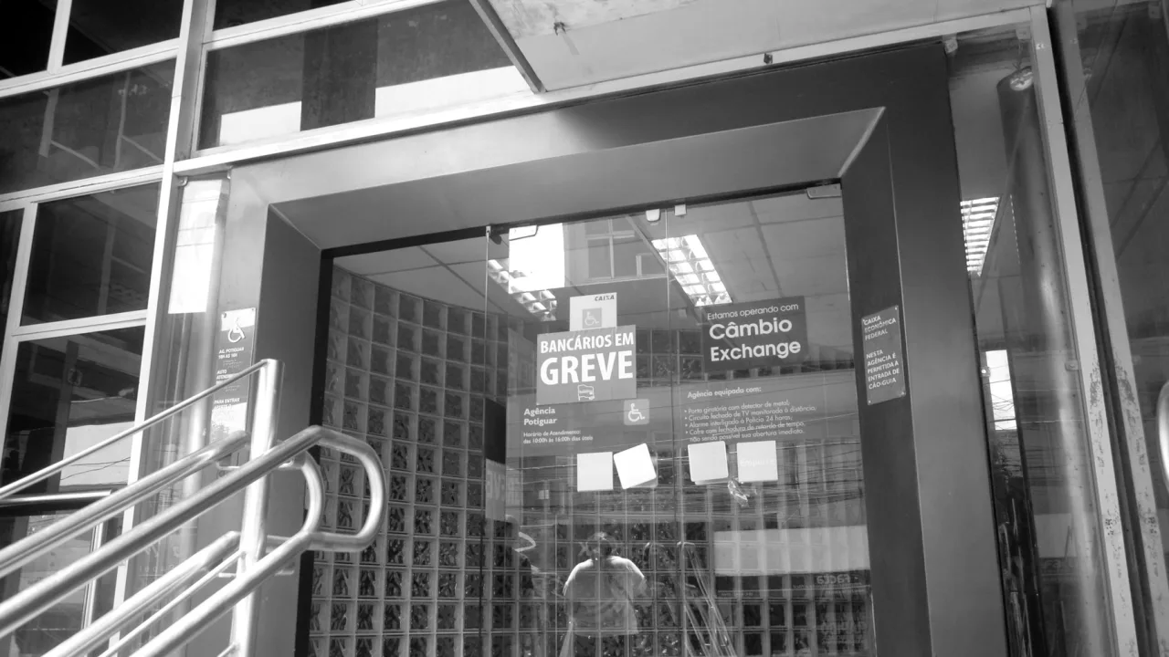 Fachada de agência da Caixa Econômica Federal com aviso de greve.