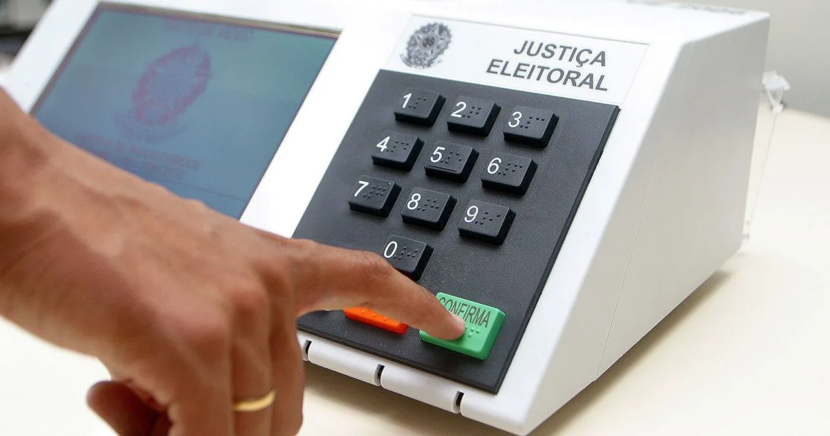 Cidadão votando na urna eletrônica em seção eleitoral brasileira.