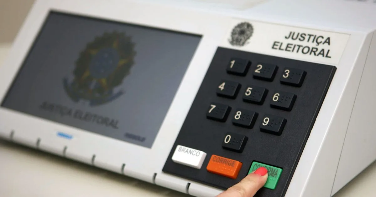 Mãos segurando um título de eleitor em ambiente corporativo.