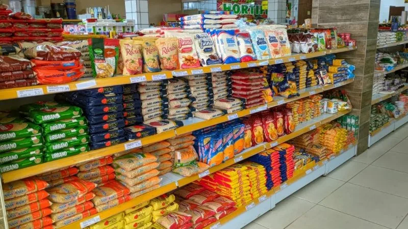 Cesta de compras contendo diversos alimentos em um supermercado.