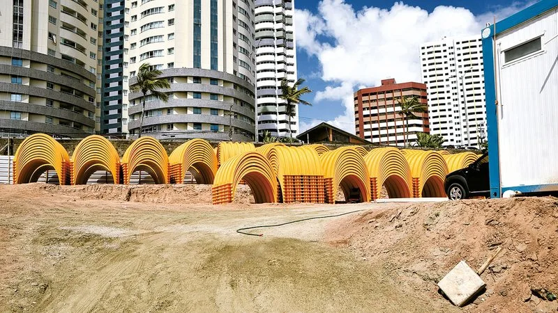 Canteiro de obras da drenagem na Praia de Ponta Negra com materiais armazenados.