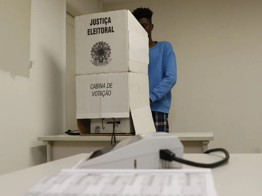 Urna eletrônica sendo utilizada por eleitor em seção eleitoral.