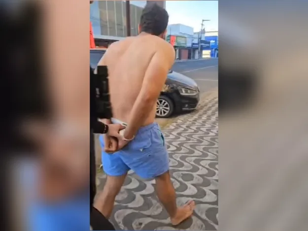 Homem algemado sendo conduzido por policiais em calçada de Mossoró.