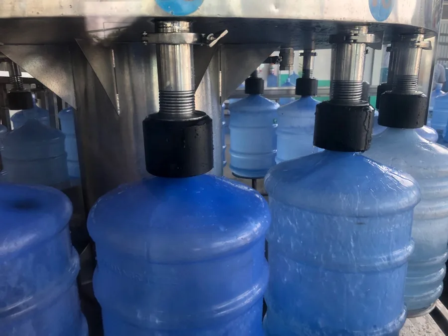 Garrafões de água mineral de 20 litros empilhados em depósito.