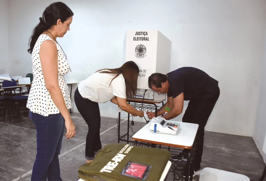 Preparação de sala de aula como seção eleitoral com urnas eletrônicas.