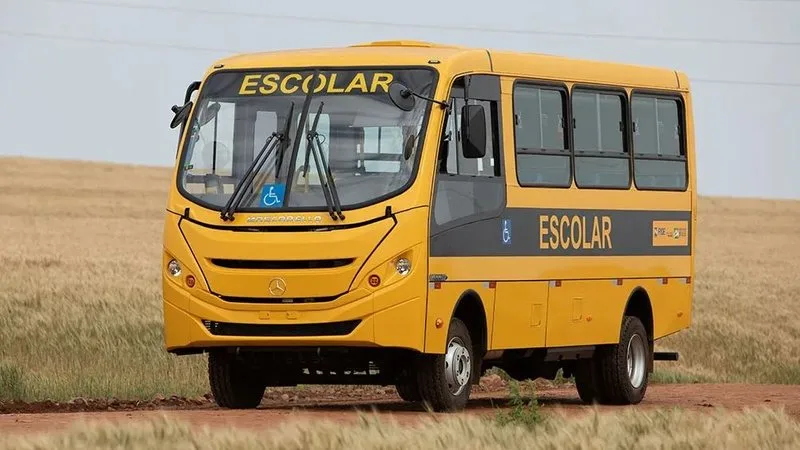Ônibus escolar amarelo sendo fiscalizado em via pública.