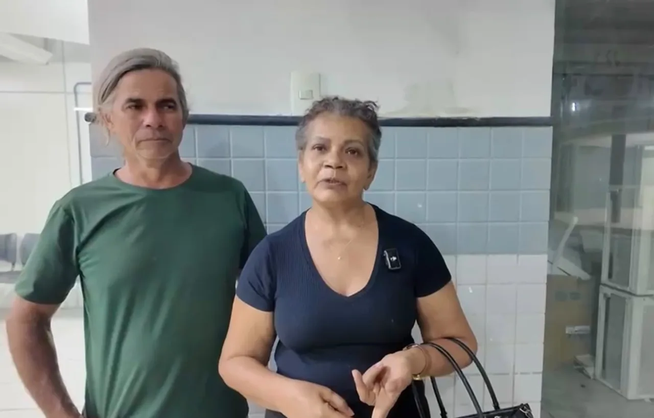 Mulher de cabelos curtos grisalhos e blusa azul-marinho aparece ao lado de um homem de cabelos grisalhos e camiseta verde.