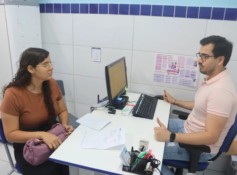 Fachada de unidade de saúde com sinalização de campanha de prevenção.