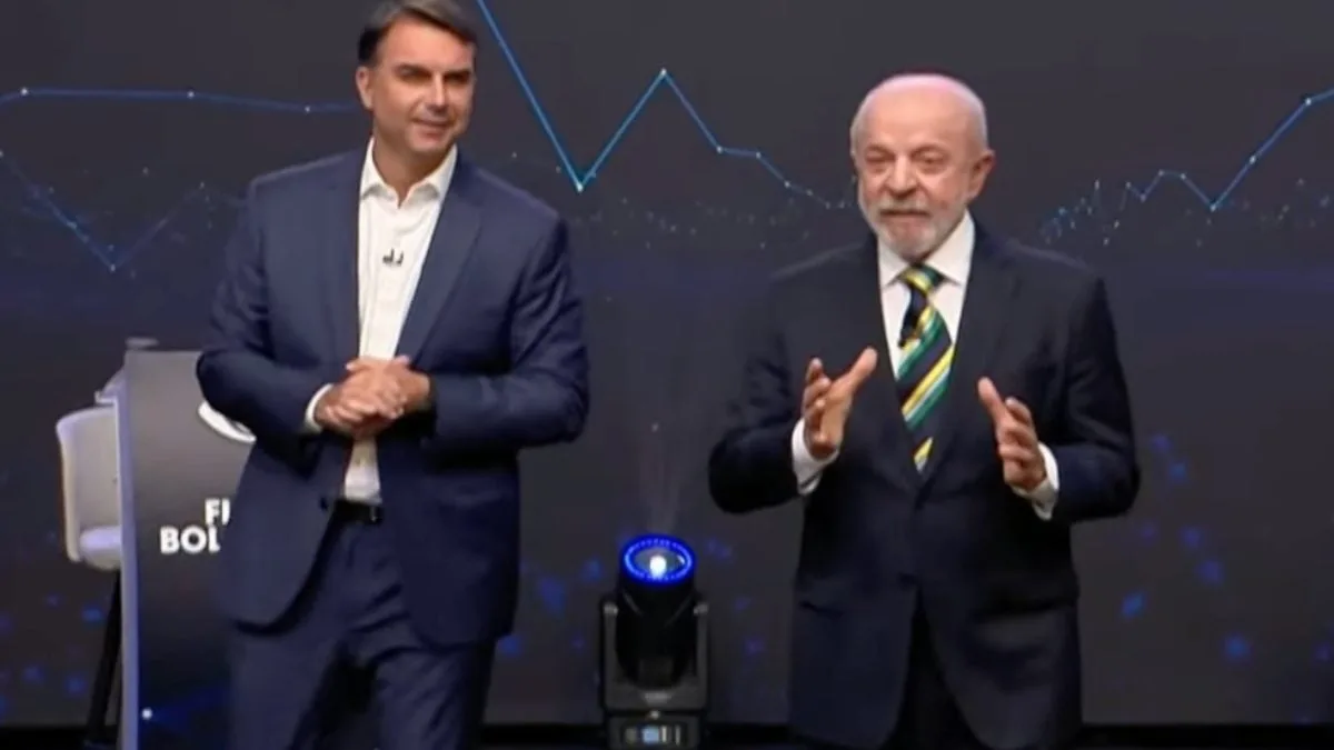 Candidatos Lula e Flávio Bolsonaro frente a frente em estúdio de TV.