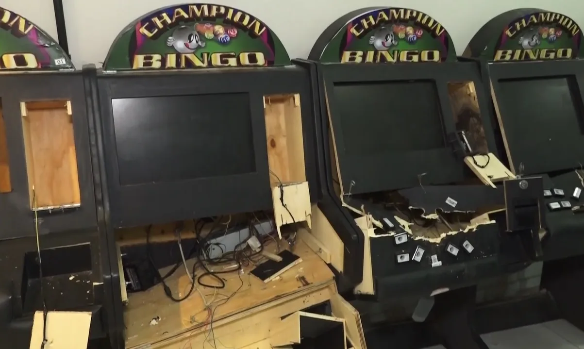 Máquinas eletrônicas pretas com identificação Champion Bingo, telas apagadas, painéis abertos, fiação exposta e partes de madeira aparentes.