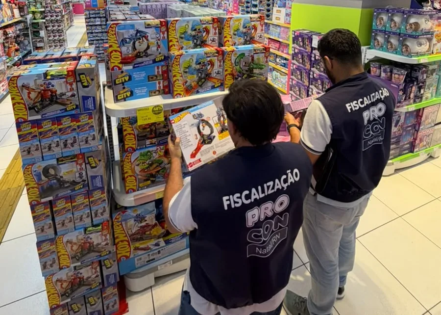 Agentes do Procon Natal fiscalizando prateleiras de brinquedos em loja.