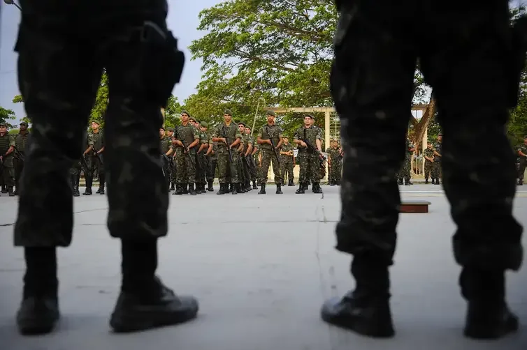 Militares uniformizados da Polícia Militar em área aberta.