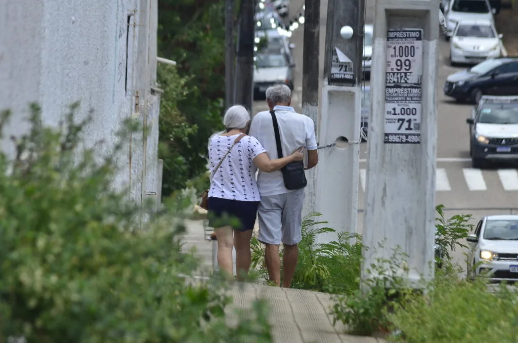 Casal de idosos caminha em ambiente urbano.