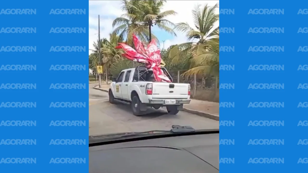 Caminhonete branca da UFRN transporta materiais políticos em sua carroceria em via pública.